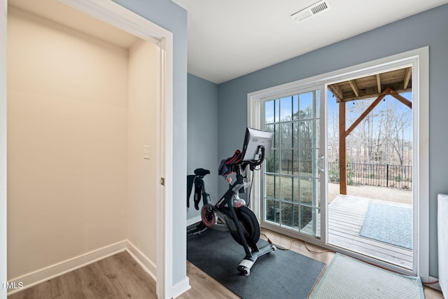 workout area featuring visible vents, baseboards, and wood finished floors