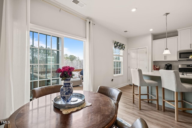 dining room with light wood-style flooring, plenty of natural light, recessed lighting, and visible vents