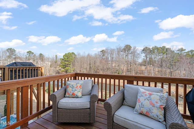 wooden terrace featuring a wooded view