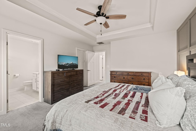 bedroom with visible vents, a tray ceiling, ceiling fan, ensuite bathroom, and carpet flooring