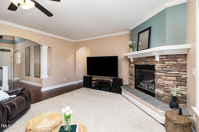 living room featuring baseboards, arched walkways, dark wood-style floors, ornamental molding, and a fireplace