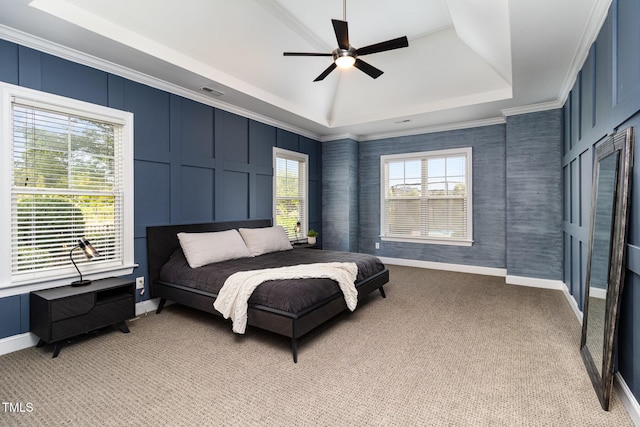 bedroom with light colored carpet, a decorative wall, visible vents, baseboards, and a tray ceiling