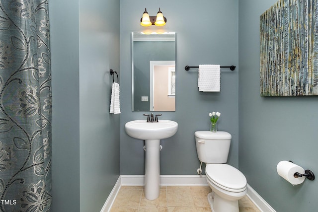 bathroom with a shower with shower curtain, tile patterned floors, toilet, and baseboards