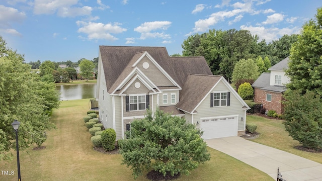 view of front facade featuring an attached garage, a water view, driveway, roof with shingles, and a front yard