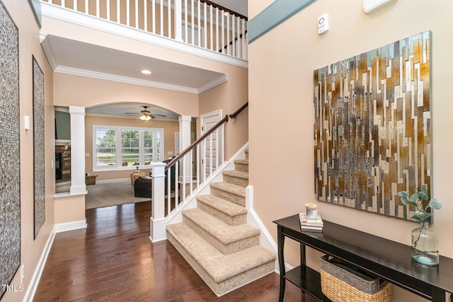 entrance foyer with baseboards, wood finished floors, crown molding, ornate columns, and a fireplace