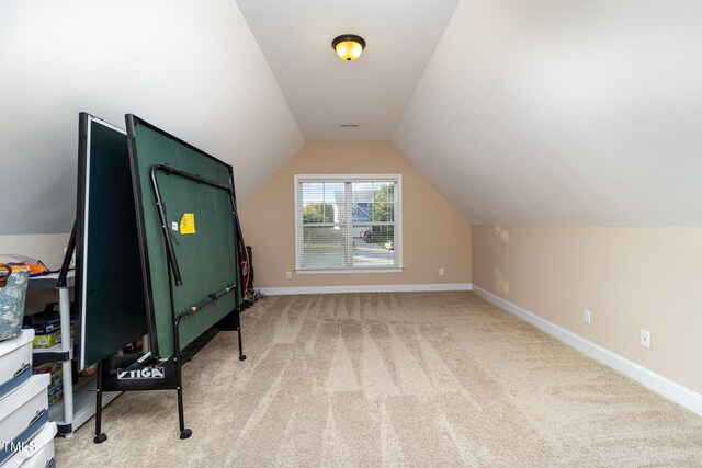 recreation room featuring baseboards, lofted ceiling, visible vents, and light colored carpet