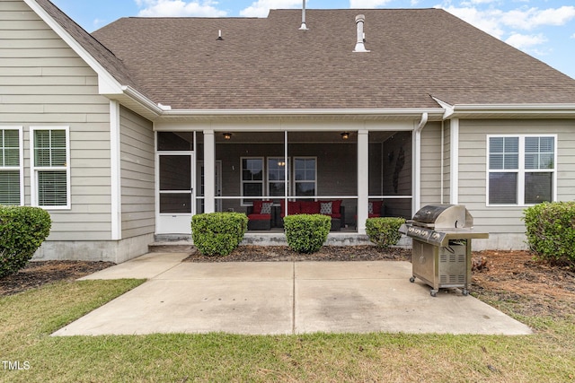 rear view of house featuring a sunroom, a patio area, a lawn, and roof with shingles