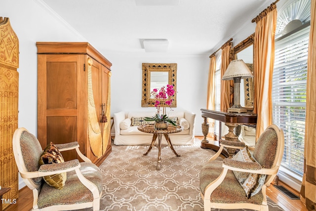 living area featuring light wood finished floors, crown molding, visible vents, and a wealth of natural light