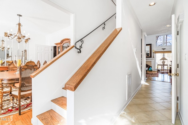 staircase with a chandelier, tile patterned flooring, recessed lighting, a fireplace, and baseboards