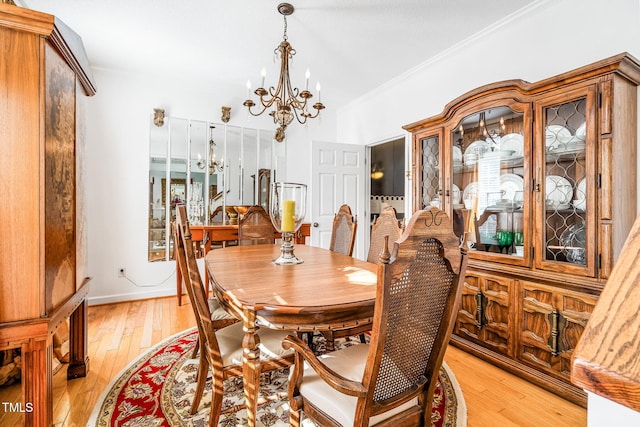 dining space featuring crown molding, light wood-type flooring, baseboards, and a notable chandelier