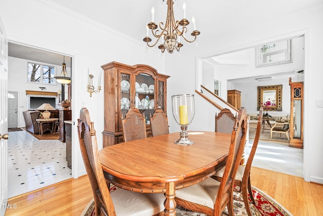 dining area with light wood-style flooring, ornamental molding, and a notable chandelier