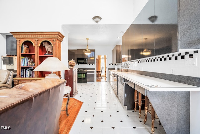 kitchen featuring black microwave, hanging light fixtures, tasteful backsplash, and a sink