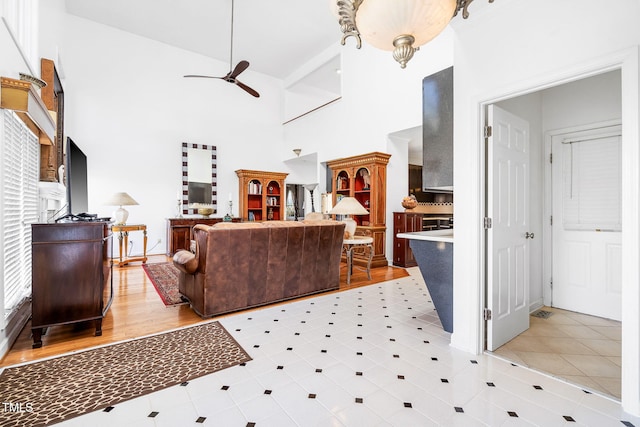 living room featuring a ceiling fan and a high ceiling