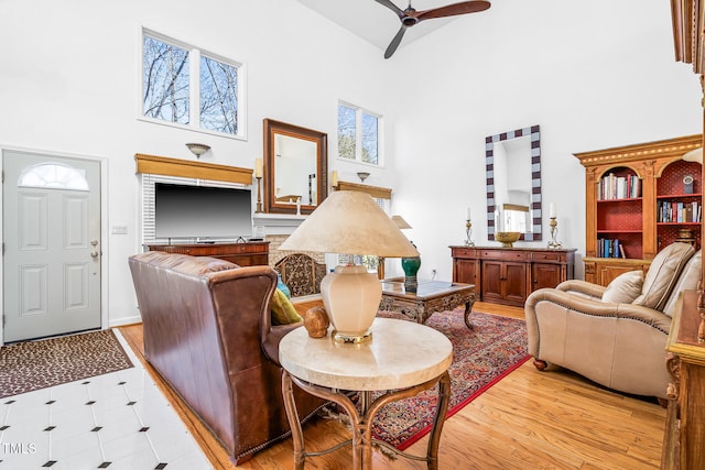 sitting room featuring a towering ceiling, light wood-style flooring, and a ceiling fan