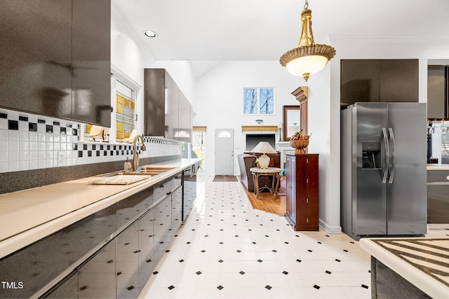 kitchen featuring hanging light fixtures, crown molding, stainless steel refrigerator with ice dispenser, and backsplash