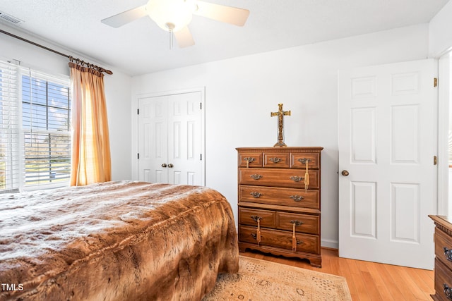 bedroom featuring light wood finished floors, a closet, visible vents, and a ceiling fan