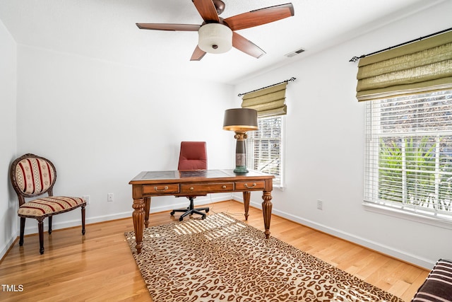 office featuring light wood-style floors, a wealth of natural light, visible vents, and a ceiling fan