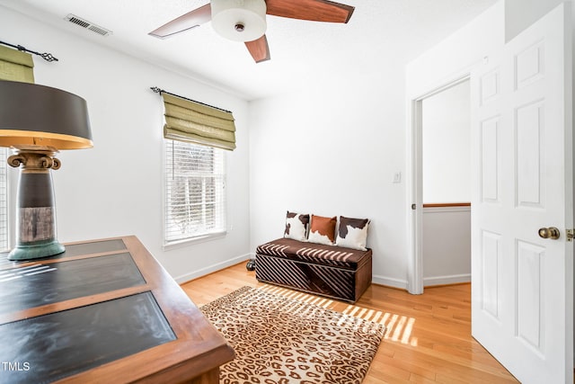 living area featuring light wood-type flooring, visible vents, ceiling fan, and baseboards