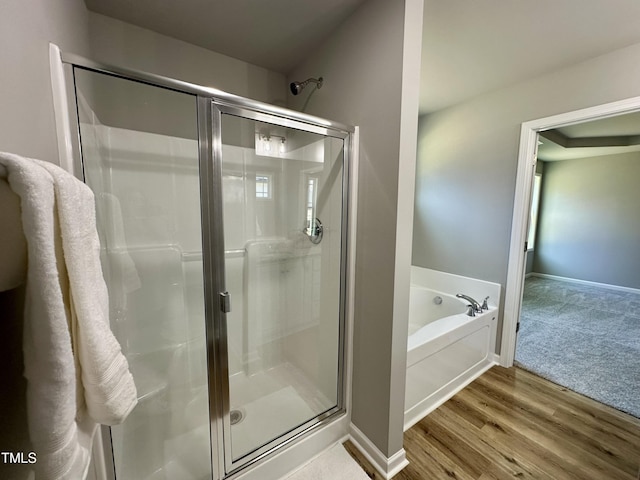 full bath with a garden tub, wood finished floors, a stall shower, and baseboards