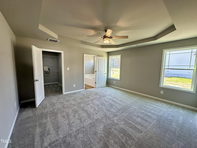 unfurnished bedroom with visible vents, multiple windows, baseboards, carpet, and a raised ceiling