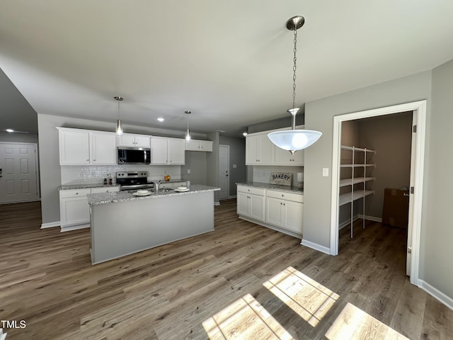 kitchen with white cabinets, backsplash, wood finished floors, and appliances with stainless steel finishes