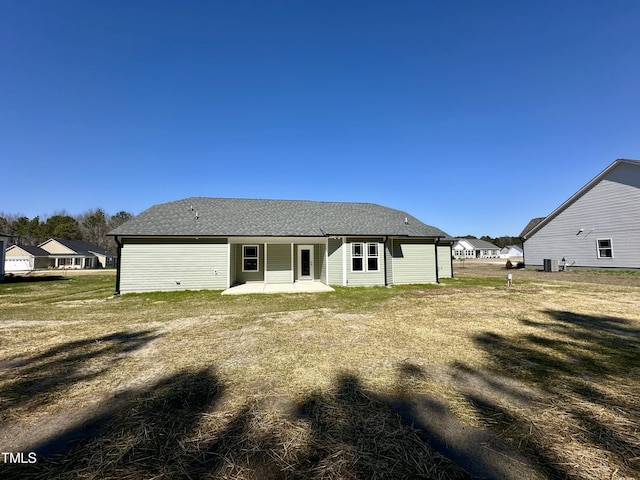 back of house featuring a patio, a lawn, and a shingled roof