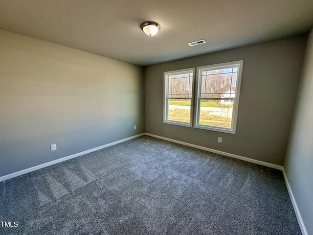 unfurnished room with visible vents, dark carpet, and baseboards