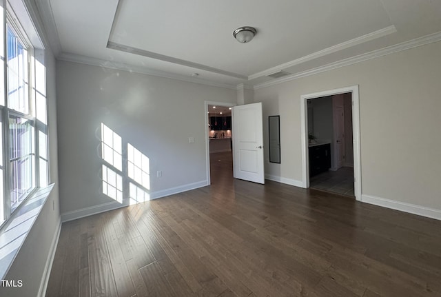 spare room featuring crown molding, baseboards, dark wood finished floors, and a wealth of natural light