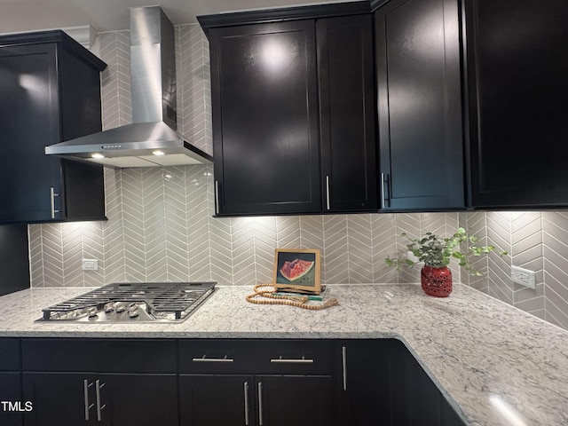 kitchen featuring tasteful backsplash, dark cabinetry, stainless steel gas cooktop, and wall chimney exhaust hood