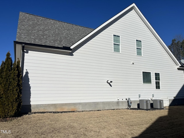 view of property exterior with central AC unit and roof with shingles