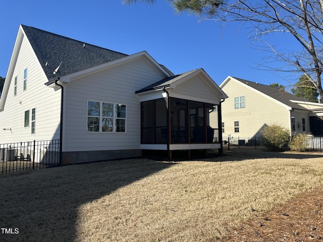 back of property featuring a yard, roof with shingles, fence, and a sunroom