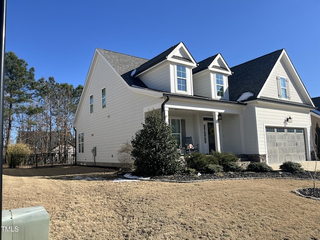 view of front of home with covered porch, stone siding, and fence