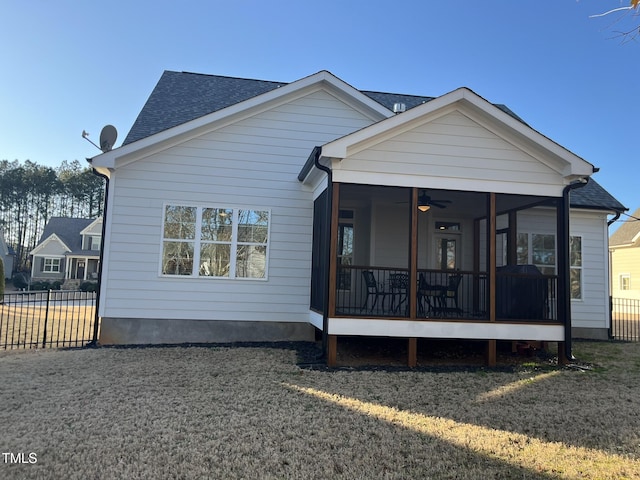 rear view of property with a sunroom, a shingled roof, fence, and a lawn