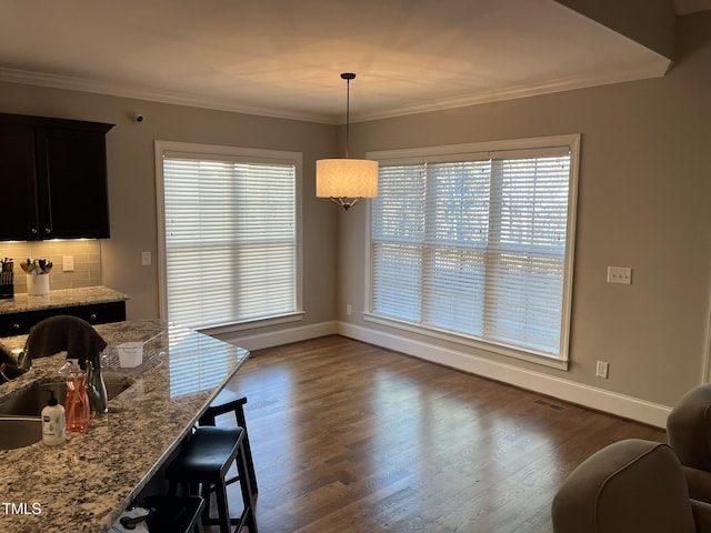 dining space featuring dark wood-style floors, baseboards, visible vents, and ornamental molding