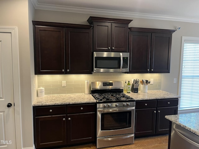 kitchen featuring light stone countertops, ornamental molding, stainless steel appliances, and backsplash