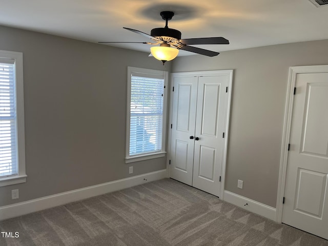 unfurnished bedroom with ceiling fan, a closet, carpet flooring, and baseboards