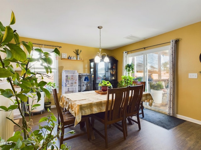 dining space featuring a chandelier, dark wood-style flooring, visible vents, and baseboards