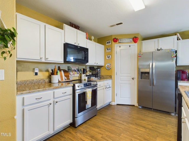 kitchen with light wood-style floors, white cabinetry, visible vents, and appliances with stainless steel finishes