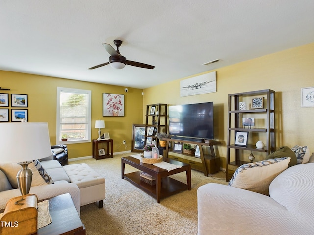 living room with visible vents, baseboards, a ceiling fan, and light colored carpet