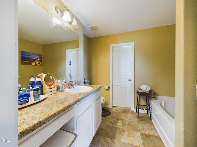 bathroom with baseboards, visible vents, toilet, a garden tub, and vanity