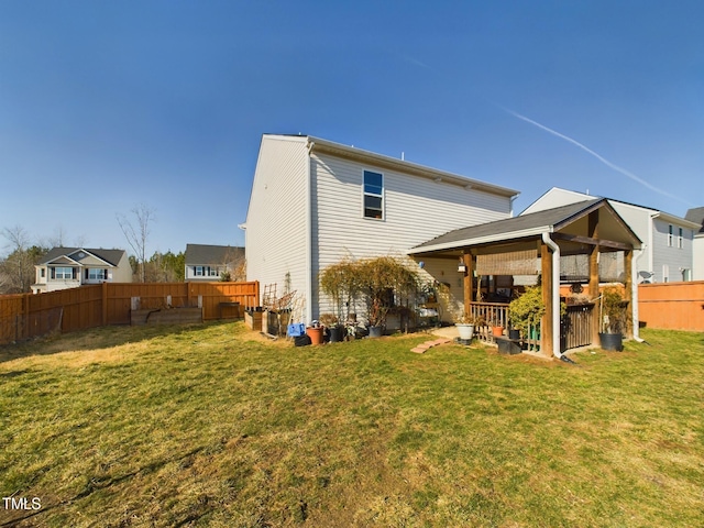 rear view of property with a lawn and a fenced backyard