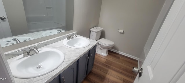 full bath with toilet, double vanity, and a sink