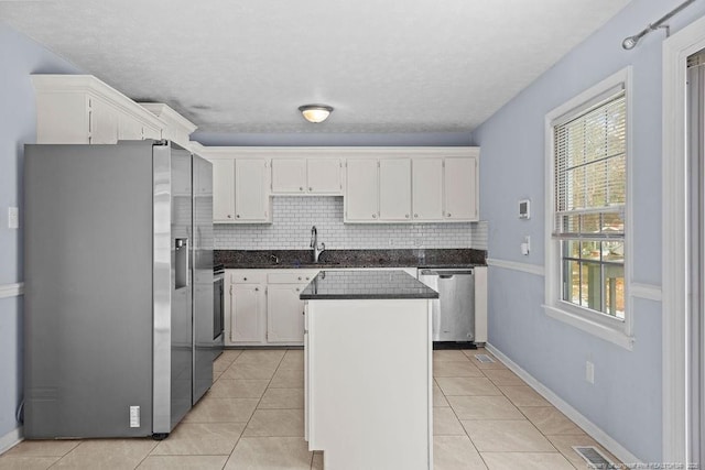 kitchen with white cabinets, light tile patterned floors, a kitchen island, and stainless steel appliances