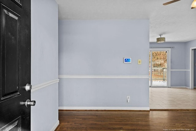 empty room with dark wood finished floors, baseboards, and ceiling fan