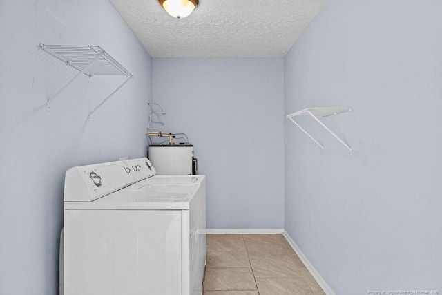 clothes washing area with light tile patterned floors, electric water heater, a textured ceiling, washer / dryer, and laundry area