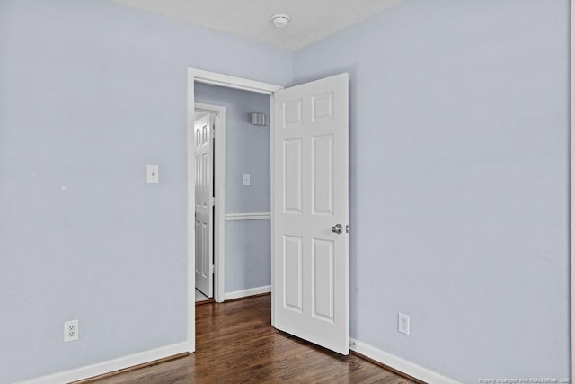 unfurnished room featuring dark wood-style floors and baseboards