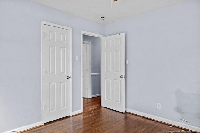 unfurnished bedroom with dark wood-style floors, baseboards, and a ceiling fan