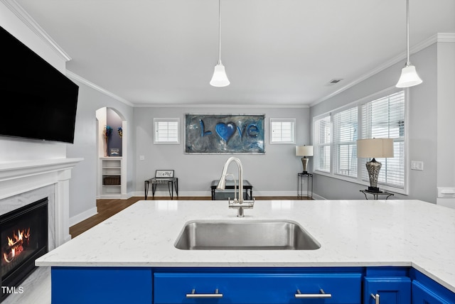 5520 Advancing Ave, Raleigh, NC 27616 - kitchen with blue cabinetry, a sink, a high end fireplace, light stone countertops, and hanging light fixtures