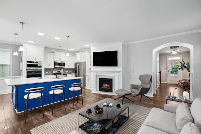 5520 Advancing Ave, Raleigh, NC 27616 - living room featuring dark wood-type flooring, arched walkways, crown molding, baseboards, and a fireplace with flush hearth