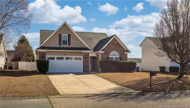 traditional home with cooling unit, brick siding, a shingled roof, fence, and concrete driveway